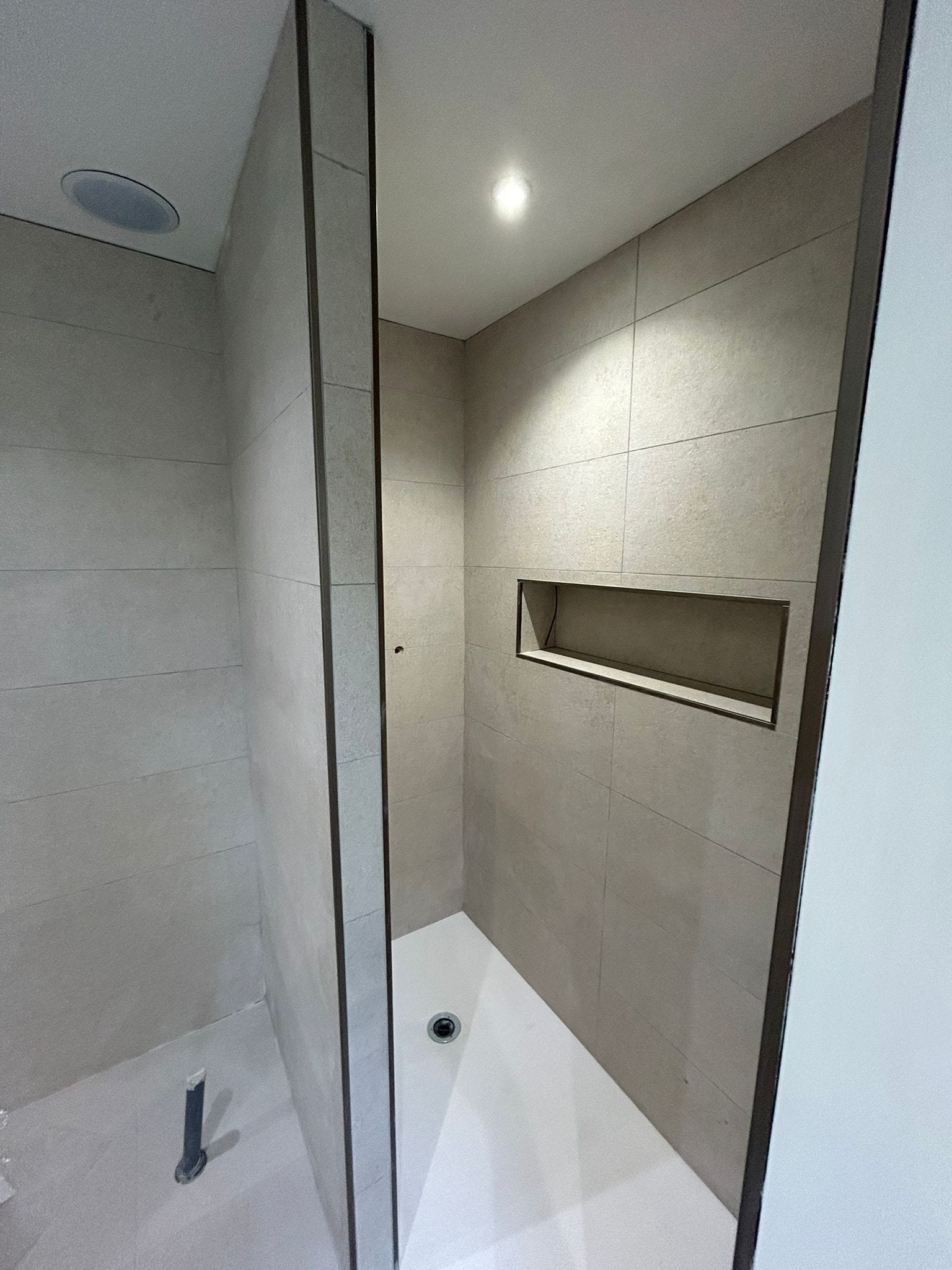 Espace douche avec niche murale et carrelage beige grand format réalisé par Yce Confort